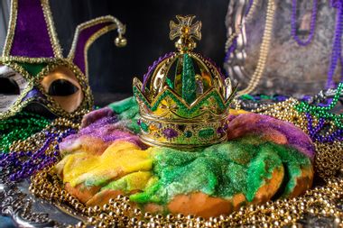 King Cake with crown surrounded by Mardi Gras beads