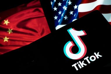 TikTok logo on a smartphone with an American and Chinese flag background