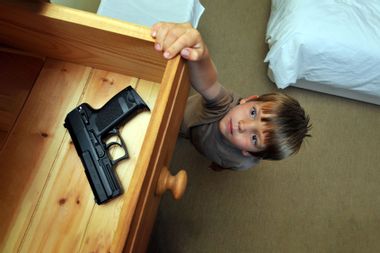 Boy reaching up to a bedroom drawer that contains a gun.