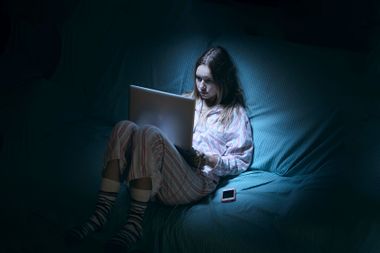A young teenager on the computer late at night