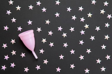 Pink menstrual cup against black background with stars
