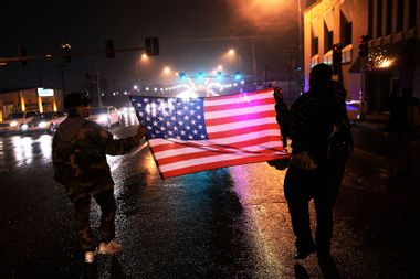 Two demonstrators march with a US flag