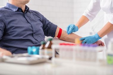 Nurse disinfecting male arm before drawing blood