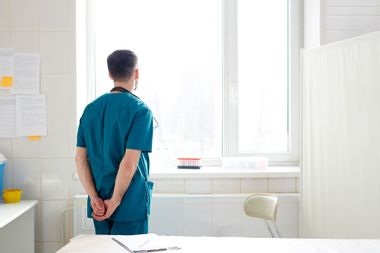 Doctor looking out window in a hospital