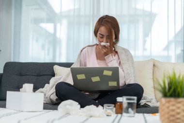 Sick woman working from home at laptop
