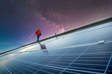 Engineer working on checking equipment in solar power plant with galaxies in the background