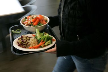 A student at the University of California, Berkeley carries a tray with organic vegetables at UC Berkeley's Crossroads dining commons.