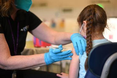 A nurse administers a pediatric dose of the Covid-19 vaccine to a girl