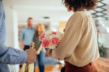 couple visiting friends with flowers and wine
