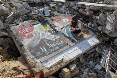 Palestinian female artist is seen drawing a picture titled 'GAZA 2024' on the concrete of the rubble of a destroyed building