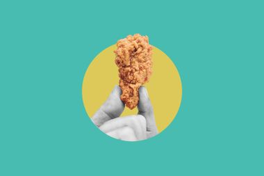 Hand holding fried chicken drumstick