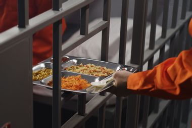 Prison guard gives food to prisoner