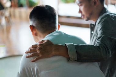 Son comforting Father hand on shoulder