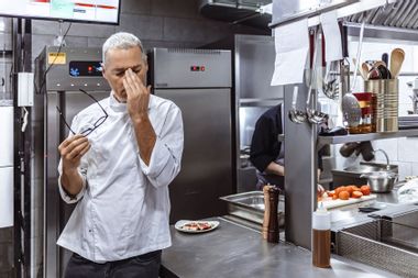 Chef at industrial kitchen in restaurant feeling burnt out