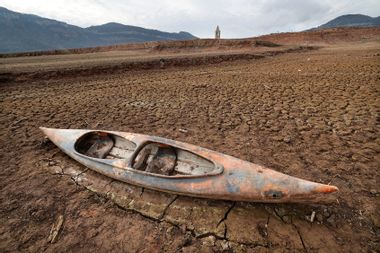 A kayak left on the dry soil next to the low water-level reservoir of Sau