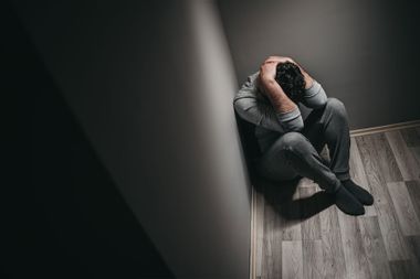 Man stressed, depressed in the corner of a room
