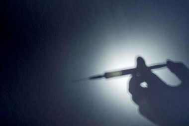 The shadow of a hand with a syringe