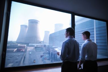 Workers looking over at nuclear power plant cooling towers