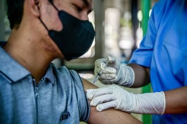 A health worker injects a man with a shot of the Inavac vaccine for Covid-19 at the Jakarta provincial health office on December 19, 2023.