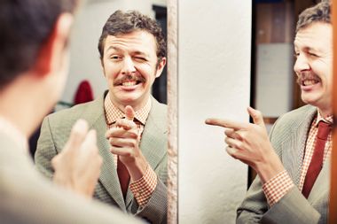 Man pointing at reflection in mirror