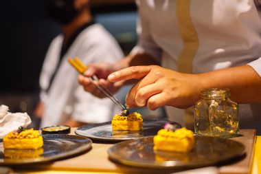 Close up hand of Japanese Sushi chef using torch burning tuna sushi for customer omakase course