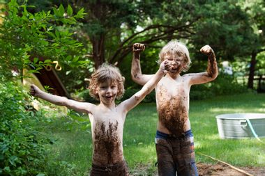 Two little boys playing in mud