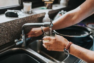 Person at a tap filling a glass of water