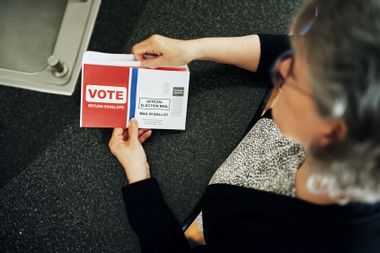 Woman looking at vote by mail ballot postcard