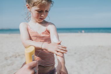 Child applying sunscreen on a beach