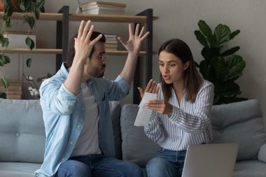 Stressed emotional couple arguing fighting when checking financial papers