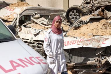 Palestinian paramedic walks past destroyed ambulances Gaza