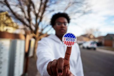 Young African American man holding an I Voted Sticker up