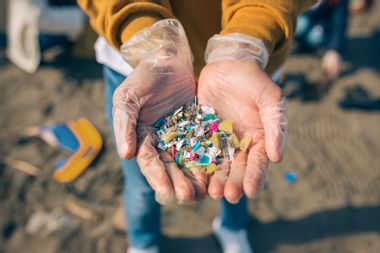 Hands holding microplastics on the beach