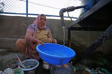 Woman utilizing water supply station Kashmir India