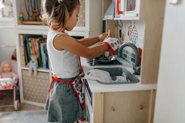 Young Girl playing in the mini play toy kitchen