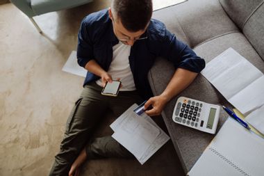 Young man at home paying his bills online