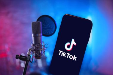 The TikTok logo displayed on a phone screen and a microphone in a recording studio.