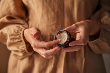 Woman using moisturizer from a jar