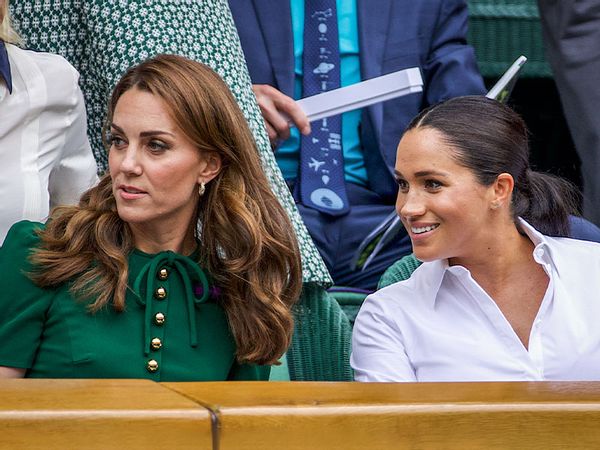 Catherine, Duchess of Cambridge sits with Meghan, Duchess of Sussex