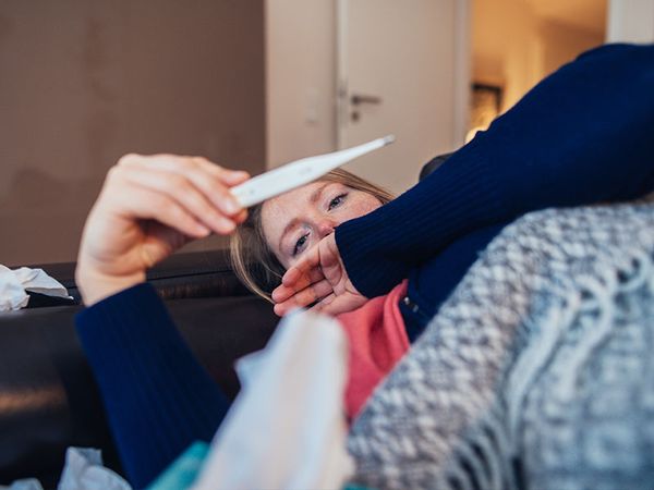 Ill woman looking at thermometer