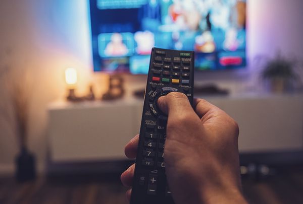 Zbliżenie ręki trzymającej pilota do telewizora