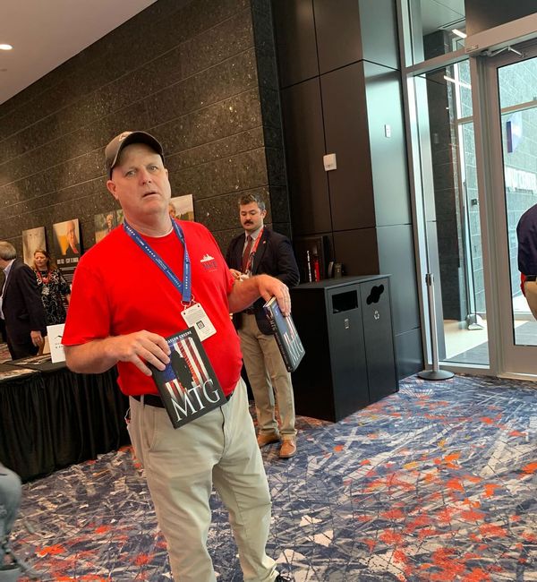 An RNC volunteer tries to tempt people to Rep. Marjorie Taylor Greene's book signing