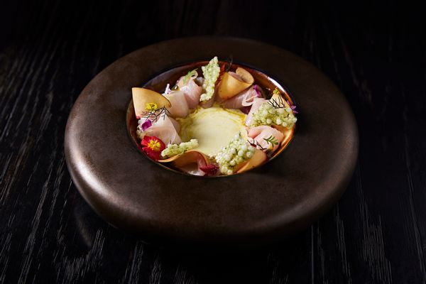 A plate of Crudo on a black table, from the restaurant Stubborn Seed.