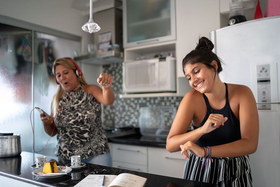 Mother and daughter having fun together while dancing in the kitchen